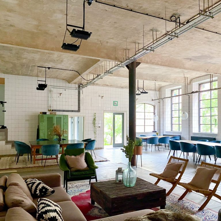 Heller, moderner Raum mit stilvollen Möbeln, Pflanzen und großen Fenstern.