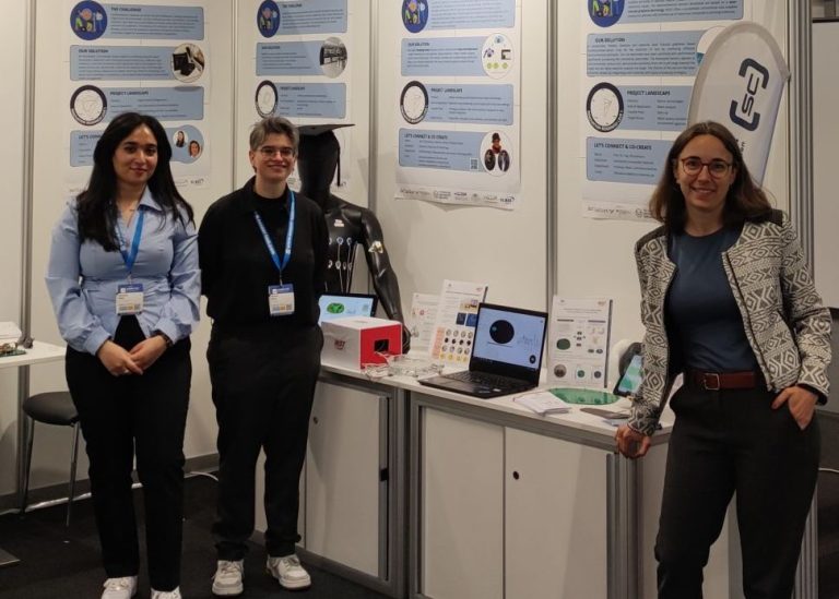 (c) SENSCUBATOR Drei Personen stehen an einem Messestand mit technischen Geräten und Informationsplakaten.