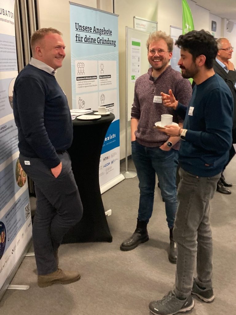 Menschen und Stände auf einer Messe, moderne Architektur und Bildschirmpräsentationen.